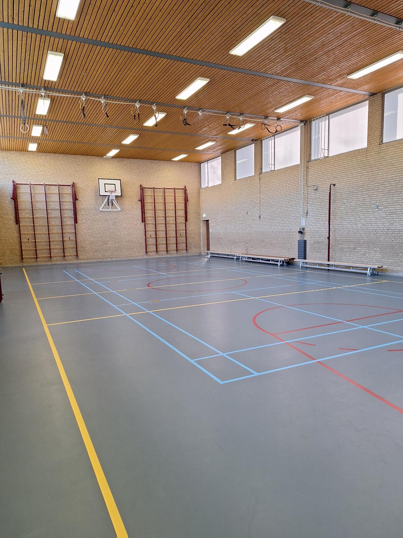 gymzaal met blauwe vloer en bakstenen muur